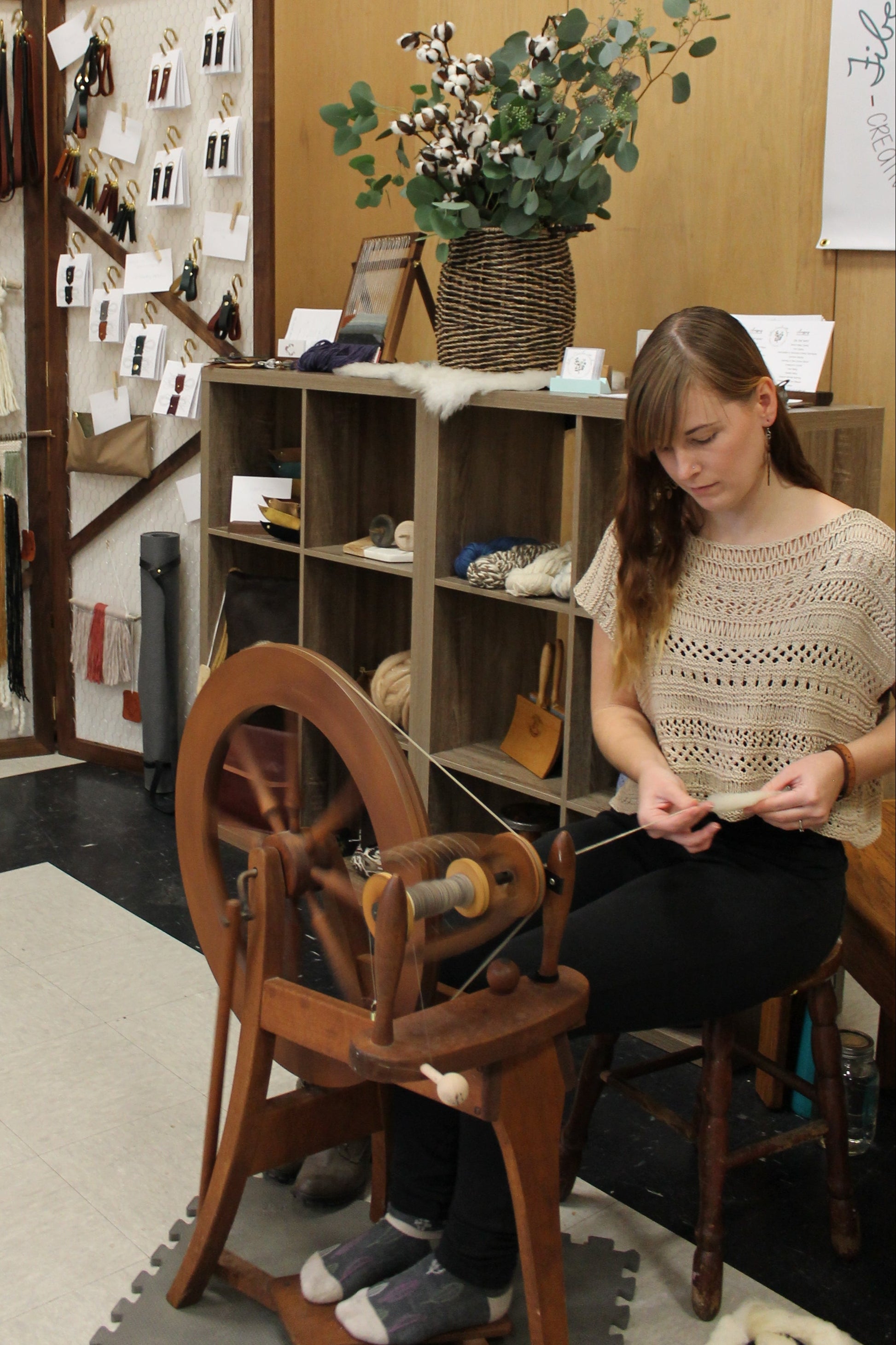 Woman working with a spinning wheel in a craft room.
