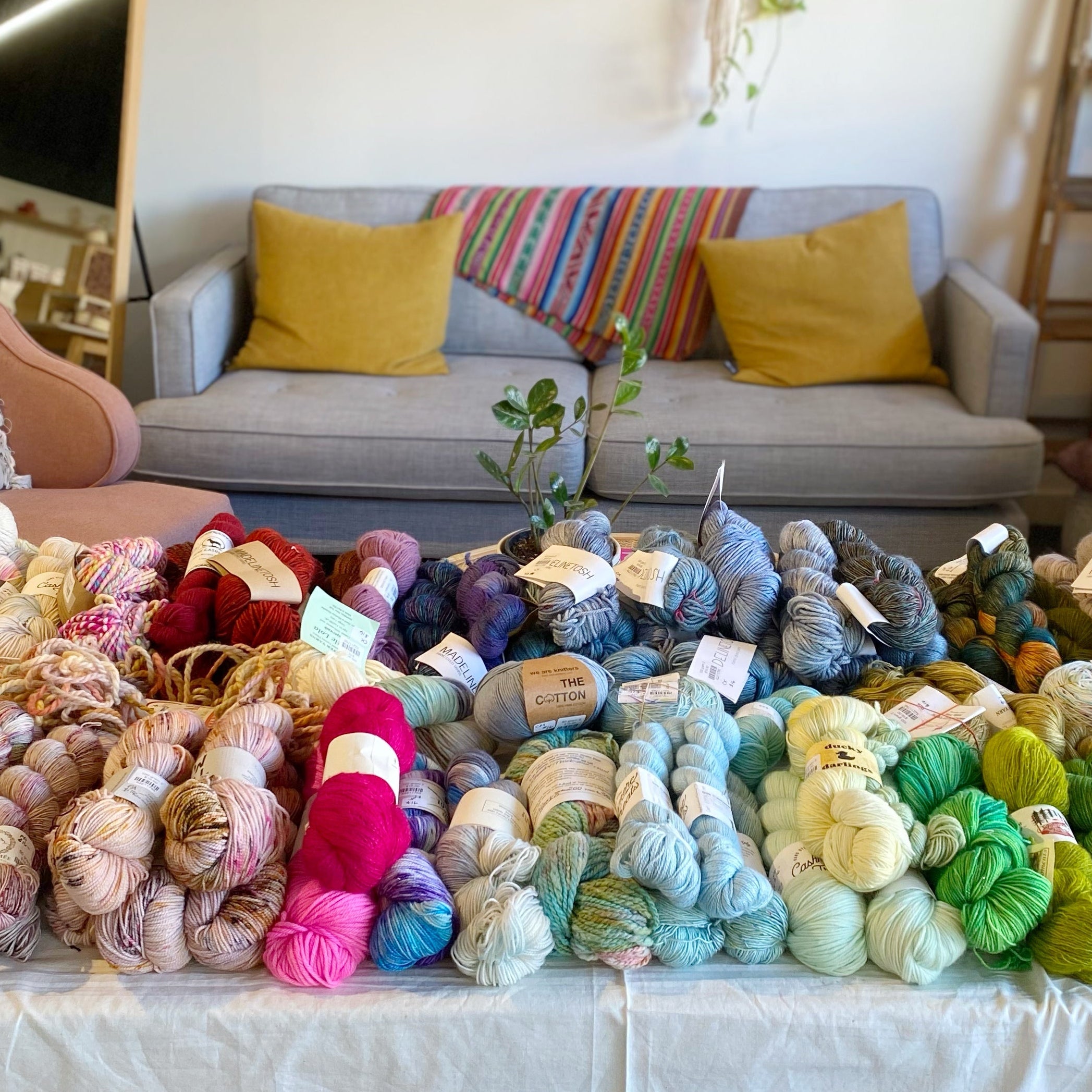 Colorful yarn skeins on a table with a living room in the background